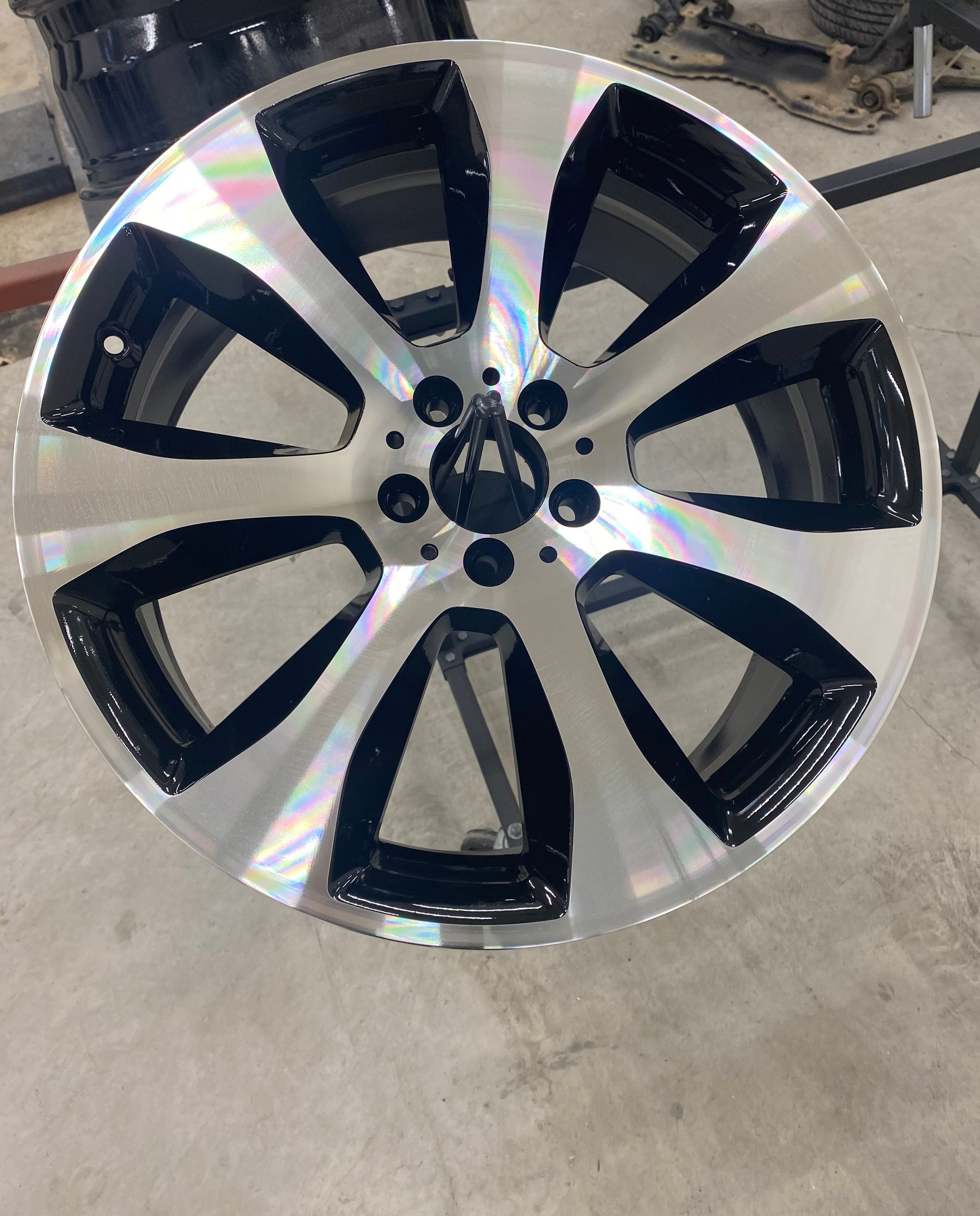 Une jante automobile multibranches arborant un design bicolore avec des faces en argent métallisé poli.