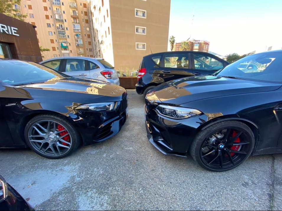 Des voitures noires garées côte à côte sur un parking, devant la carrosserie.