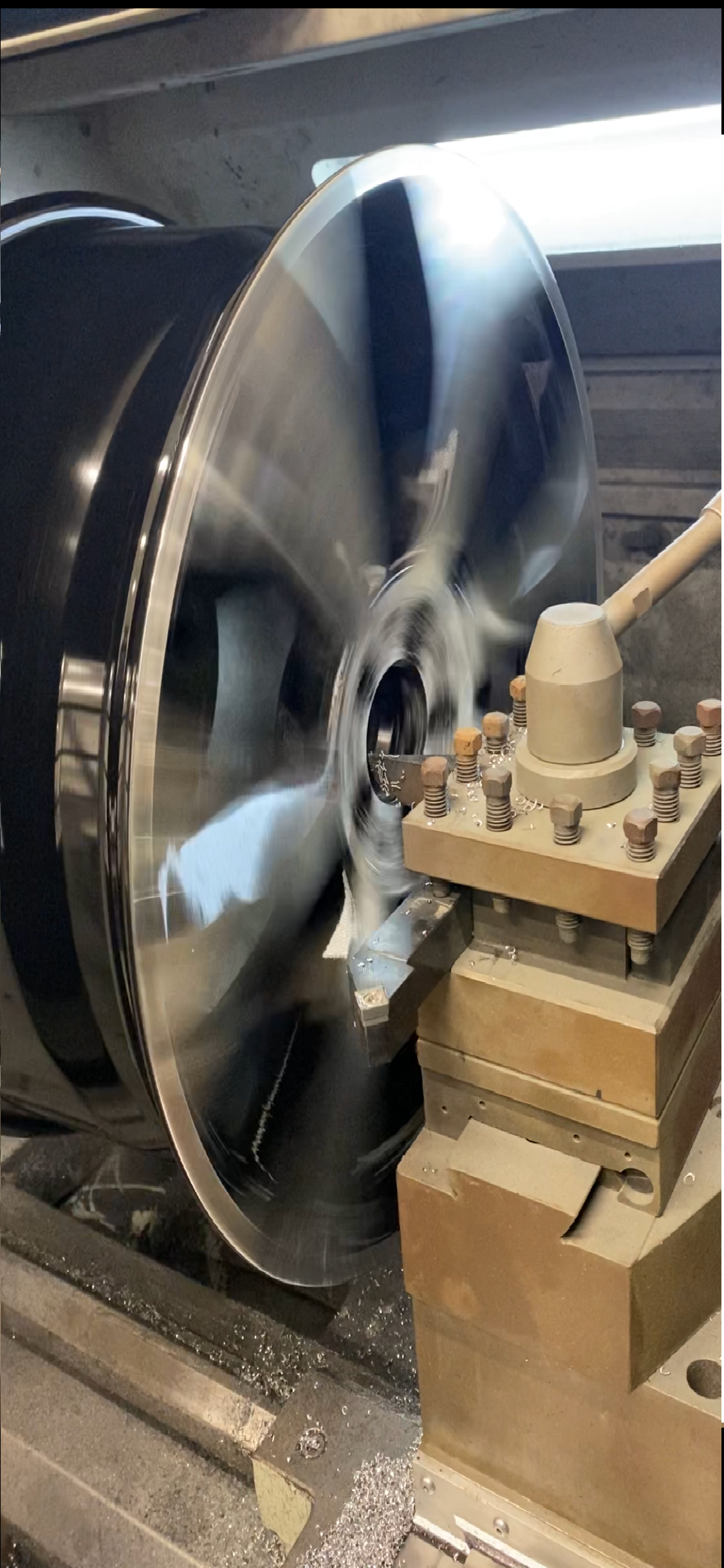 Dans un atelier, un outil de tour à métaux usine une roue circulaire en alliage.