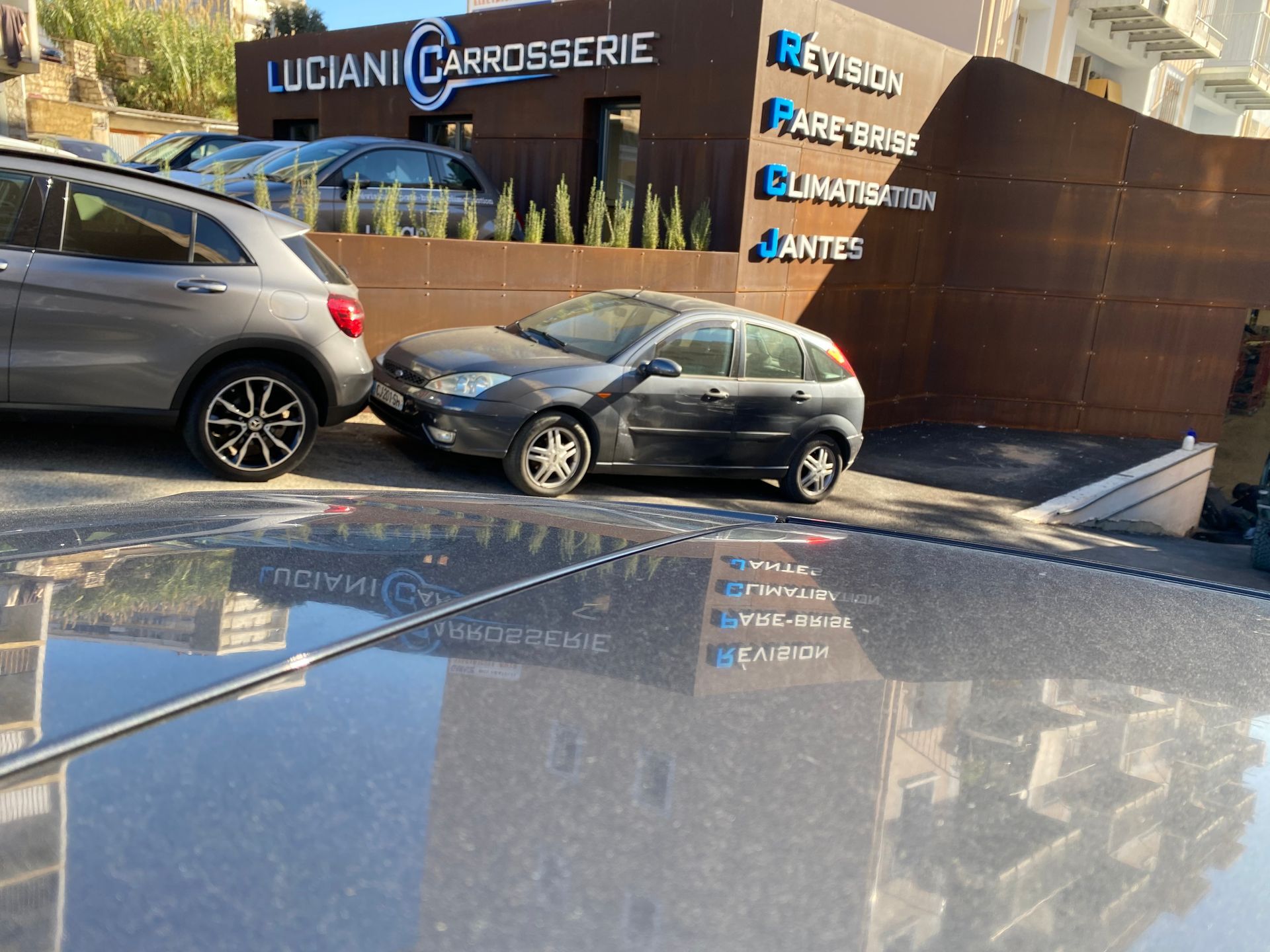 Un SUV gris et une berline garés devant le garage.