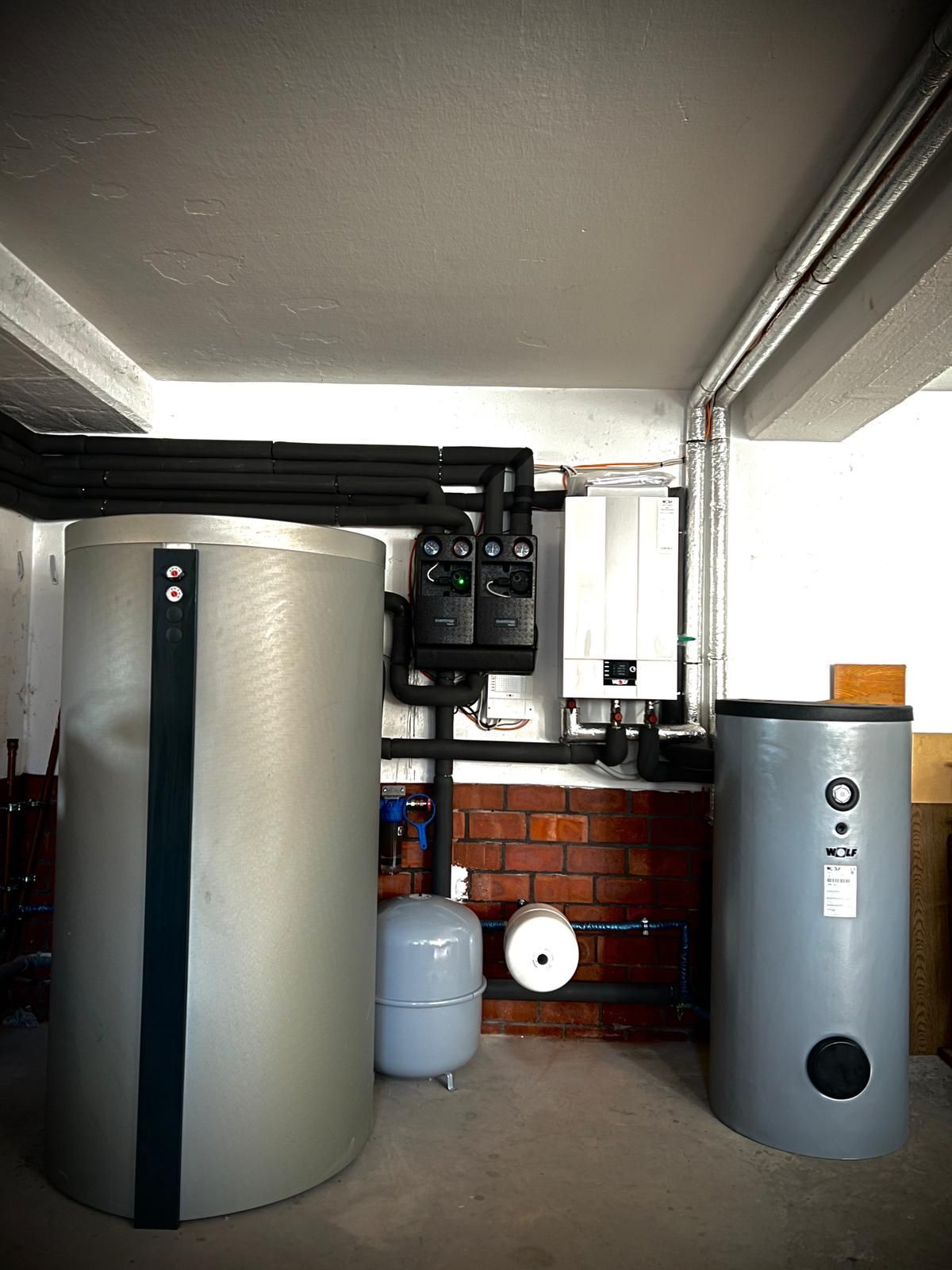 Hauswirtschaftsraum mit großen Wassertanks, Rohren und einer Ziegelwand unter einer niedrigen Decke
