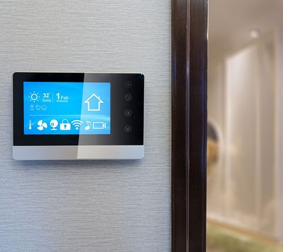Ein Smart-Home-Thermostat hängt an einer Wand neben einer Tür.