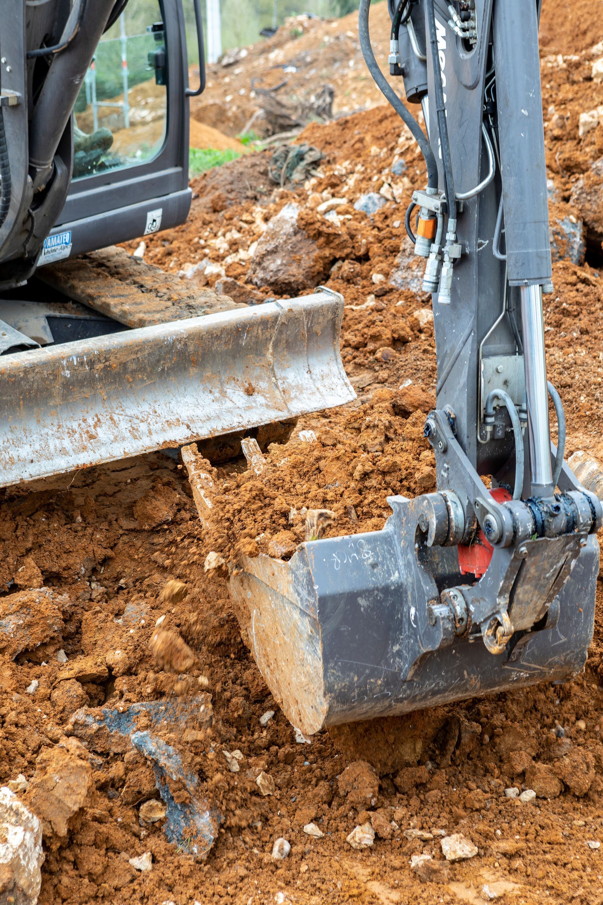 Godet d'excavatrice creusant le sol sur un chantier de construction.