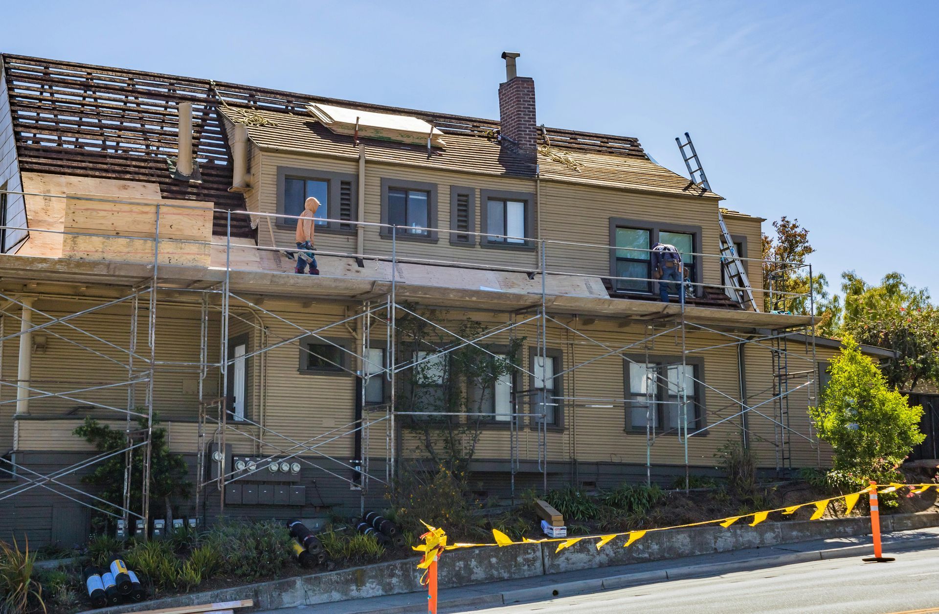 Maison à deux étages avec échafaudages et travaux de toiture.
