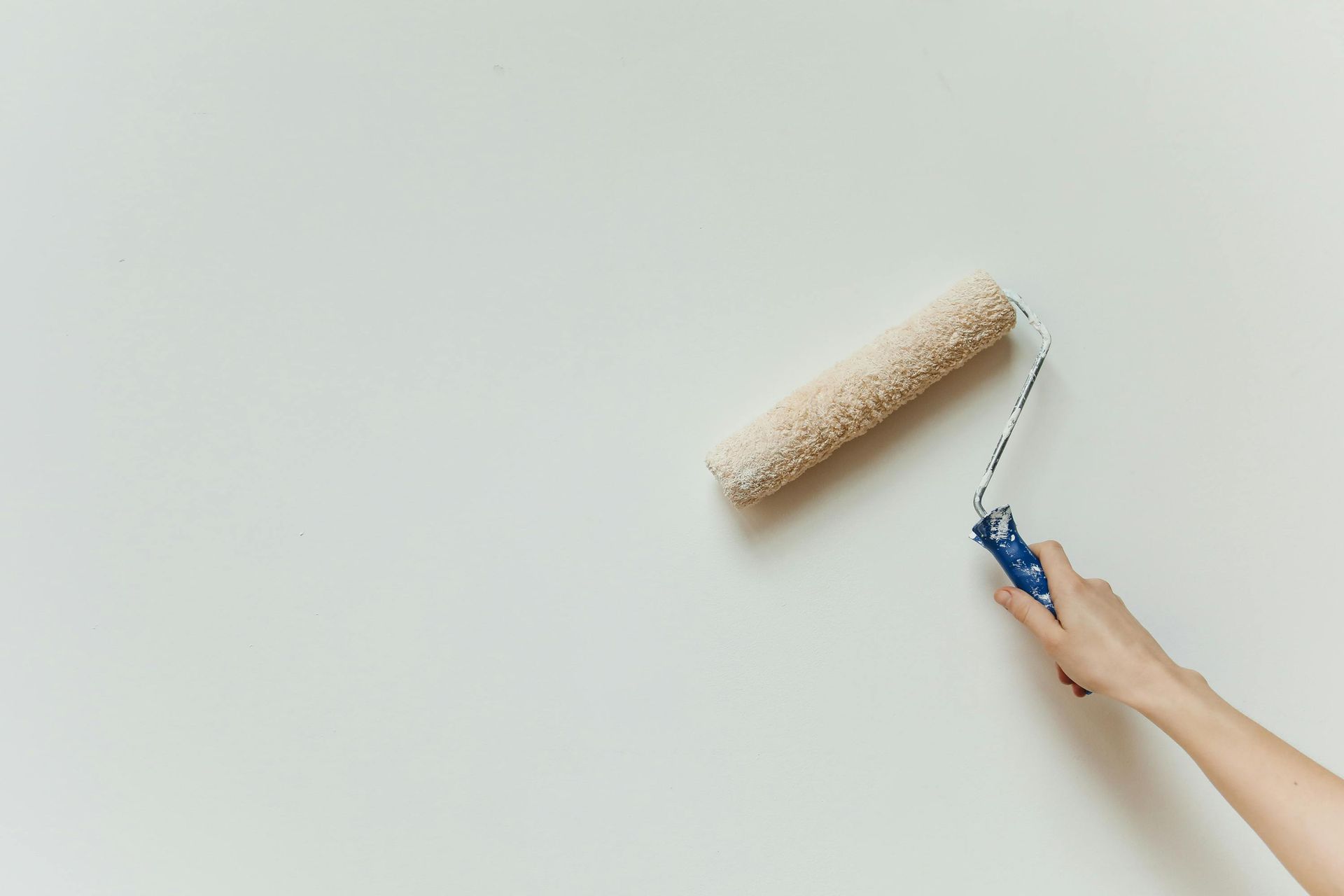 Peinture manuelle appliquée au rouleau sur un mur blanc.