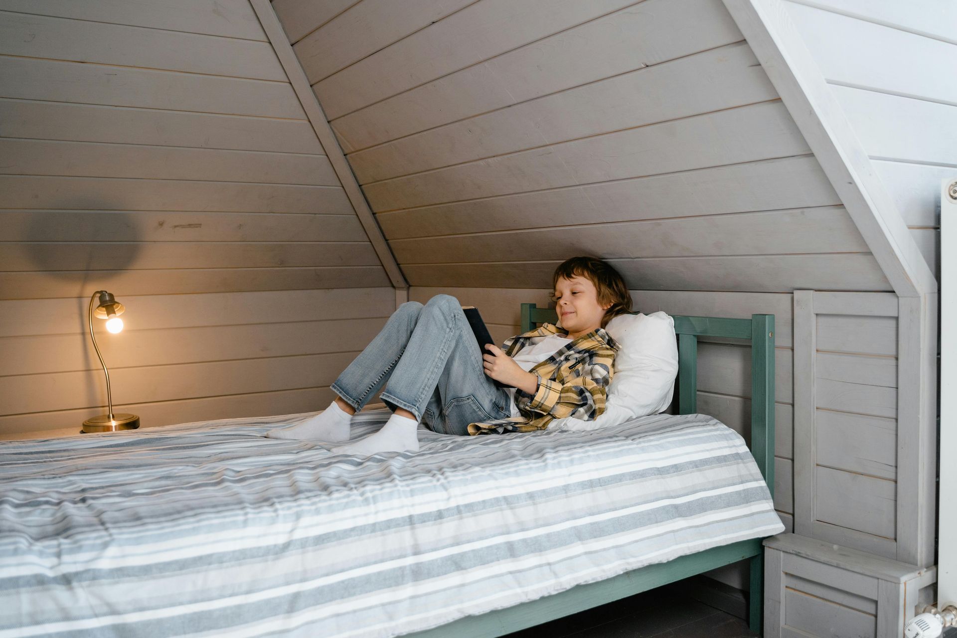 Une personne allongée sur un lit dans une petite chambre mansardée.