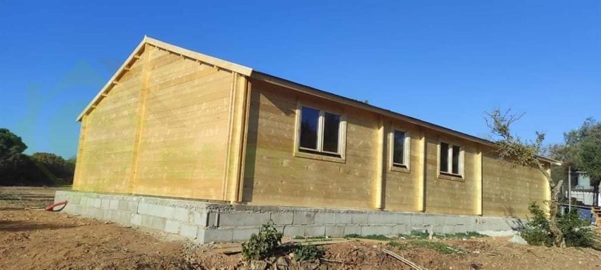 Una casa amarilla está sentada en el medio de un campo de tierra.