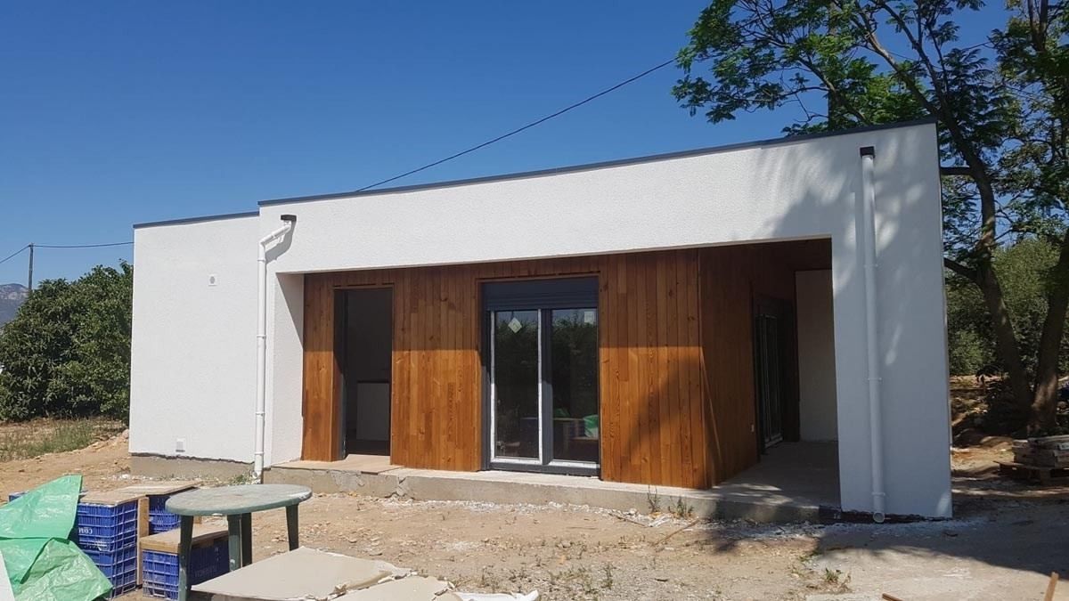 Una pequeña casa blanca con revestimiento de madera y una puerta corrediza de vidrio.