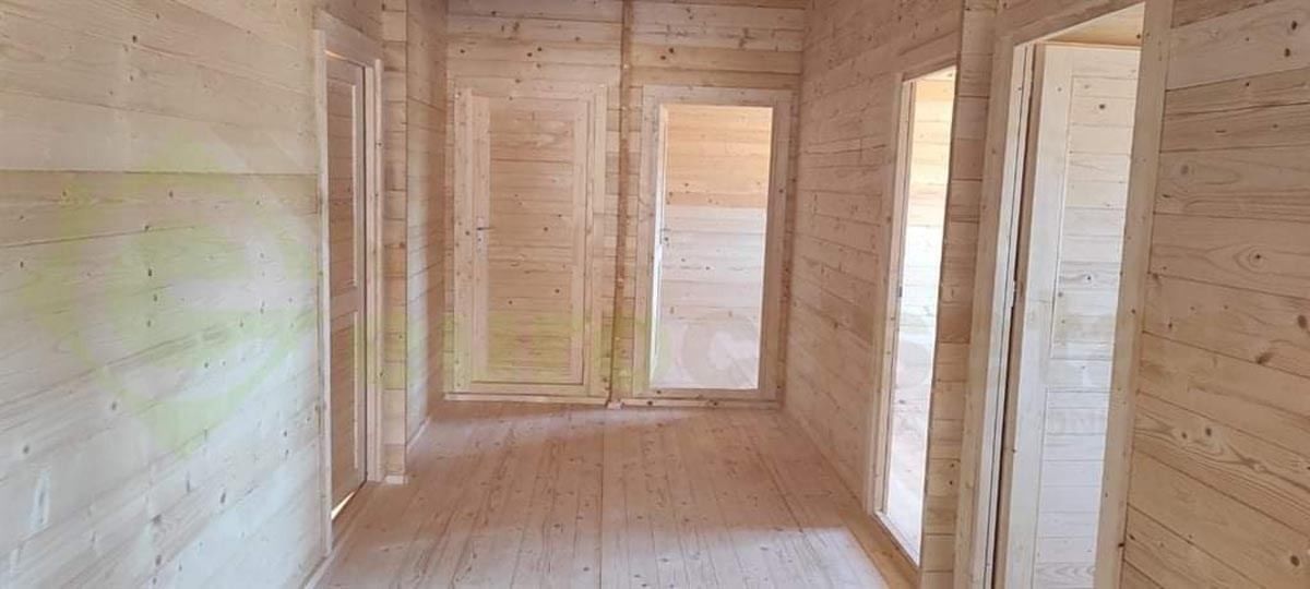 Un largo pasillo con paredes y puertas de madera en una casa de madera.