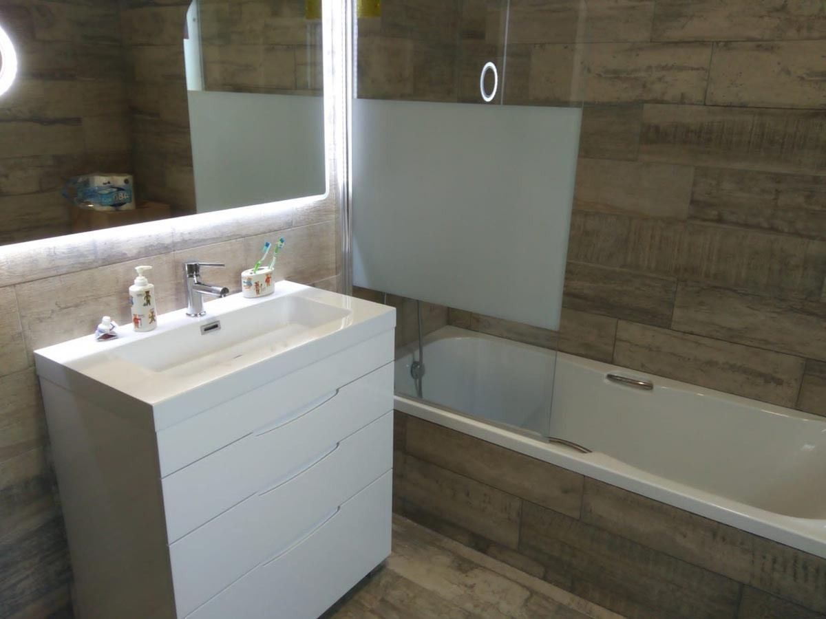 Un baño con lavabo, bañera y espejo.