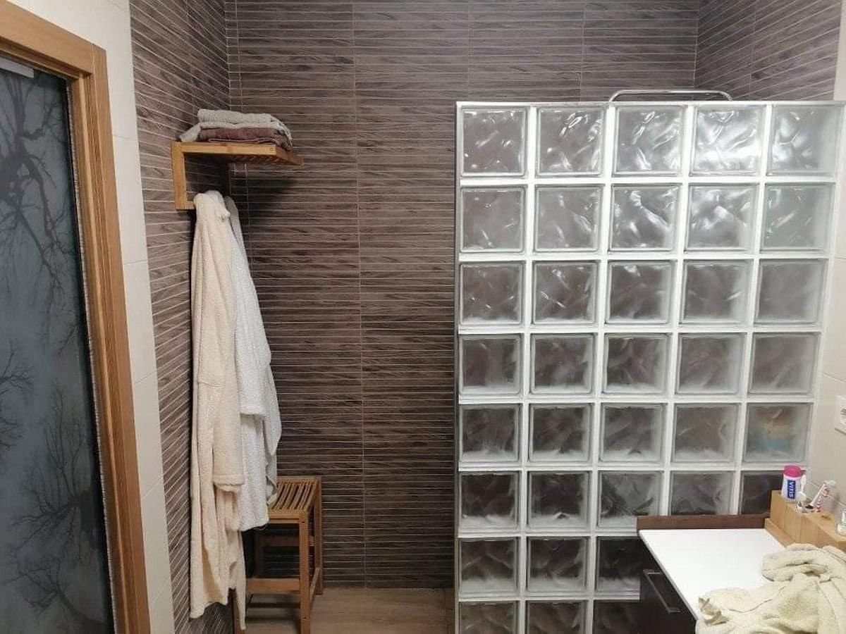 Un baño con cabina de ducha hecha de bloques de vidrio.