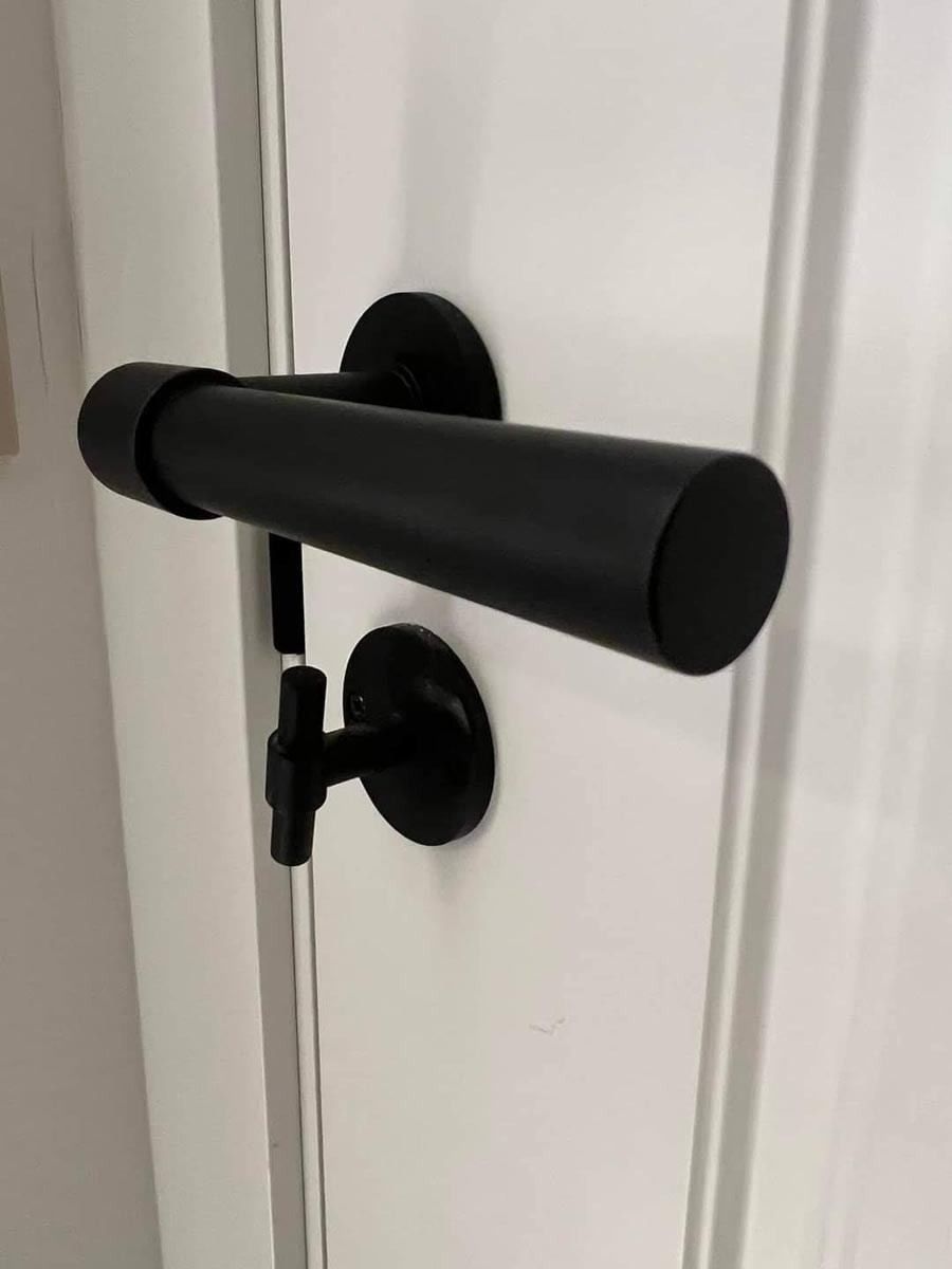 Un primer plano de una manija de puerta negra en una puerta blanca.