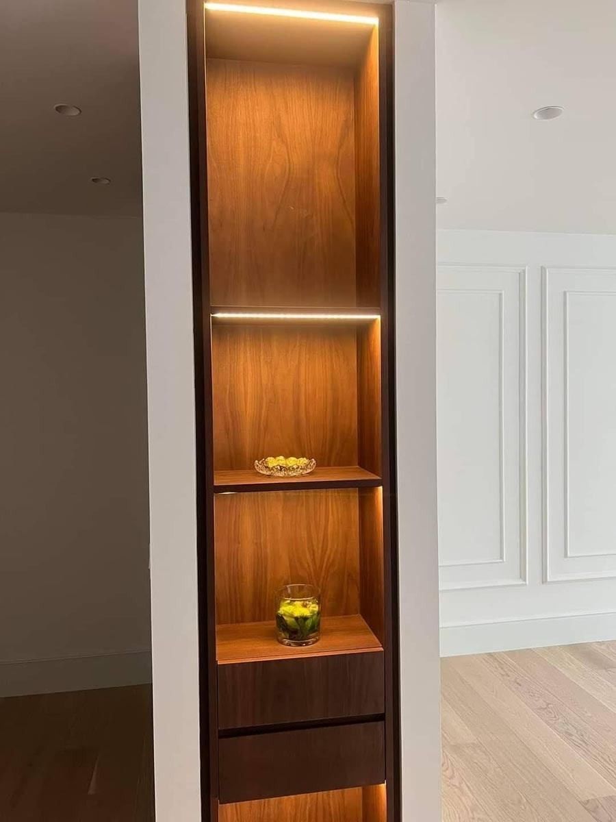 Un estante de madera con luces en los estantes de una habitación.