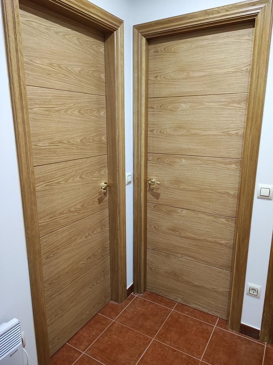 Hay dos puertas de madera una al lado de la otra en un pasillo.