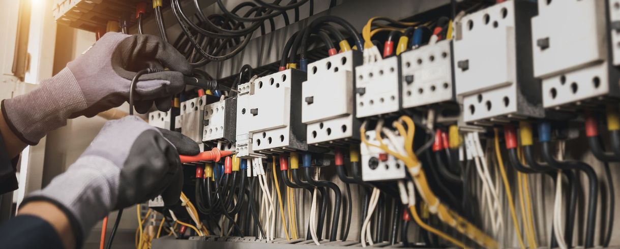 Ein Elektriker arbeitet mit einem Schraubenzieher an einem Schaltschrank.