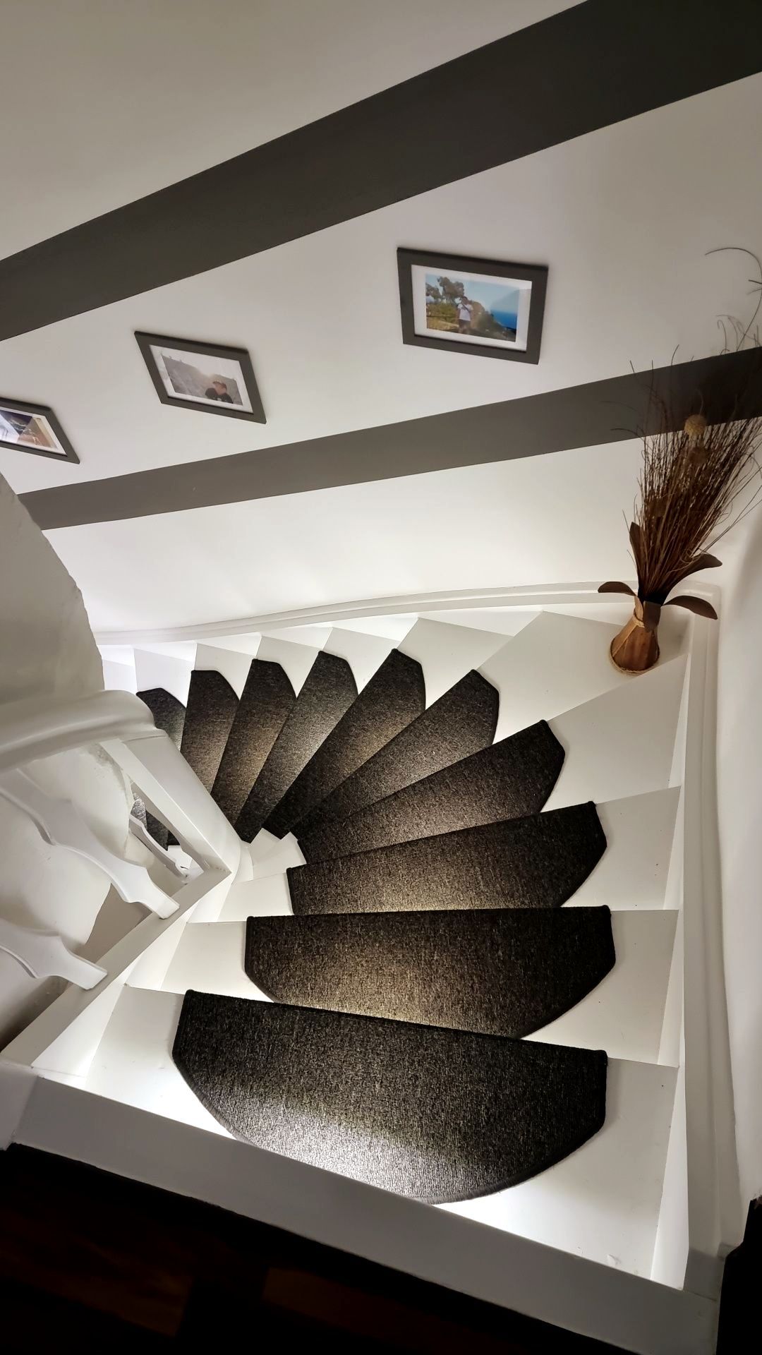 Eine Wendeltreppe mit einem schwarzen Teppich auf den Stufen führt in den zweiten Stock.