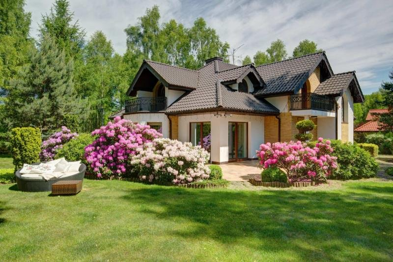 Una casa grande con un exuberante césped verde y flores en el frente.