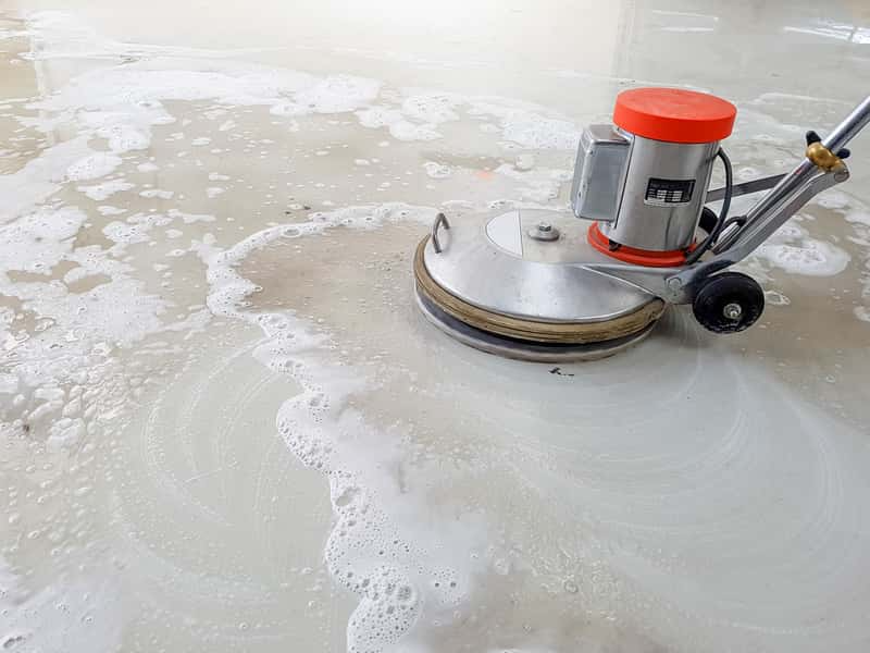Una máquina está limpiando un piso de concreto con espuma.