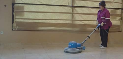 Una mujer está limpiando el suelo con una máquina.