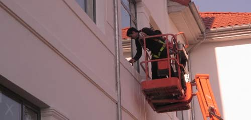 Un hombre está de pie en un ascensor al costado de un edificio.
