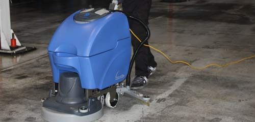 Una persona está usando una máquina para limpiar un piso de concreto.
