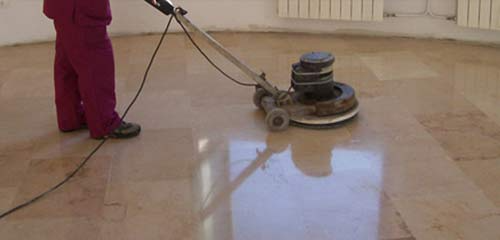 Una persona está puliendo un piso de mármol con una máquina.
