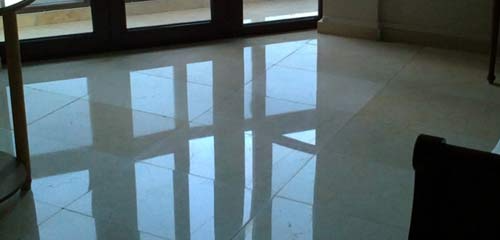 Un suelo de baldosas brillantes en una habitación con el reflejo de una ventana.
