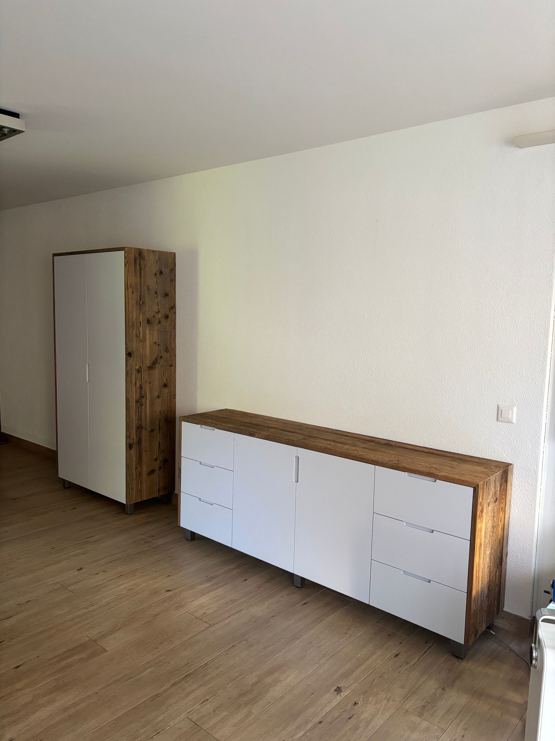 Ein Wohnzimmer mit einer Holzkommode und einem weißen Schrank.