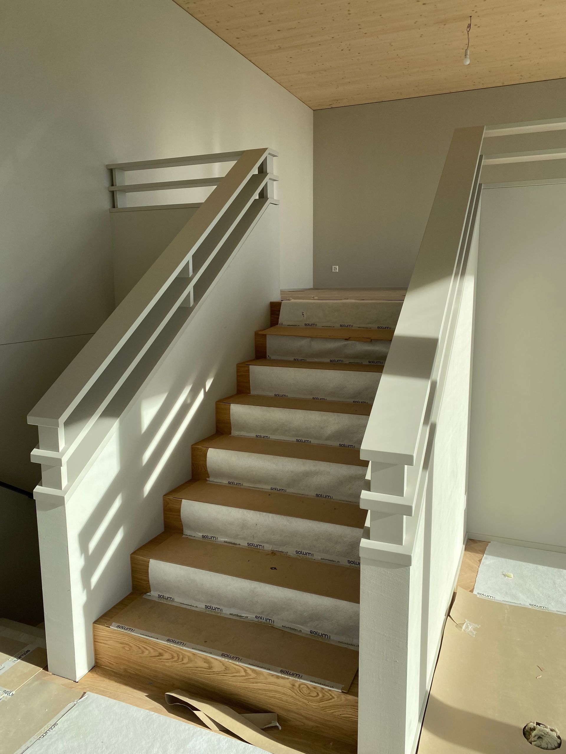 Eine Treppe mit weissem Geländer und Holzstufen