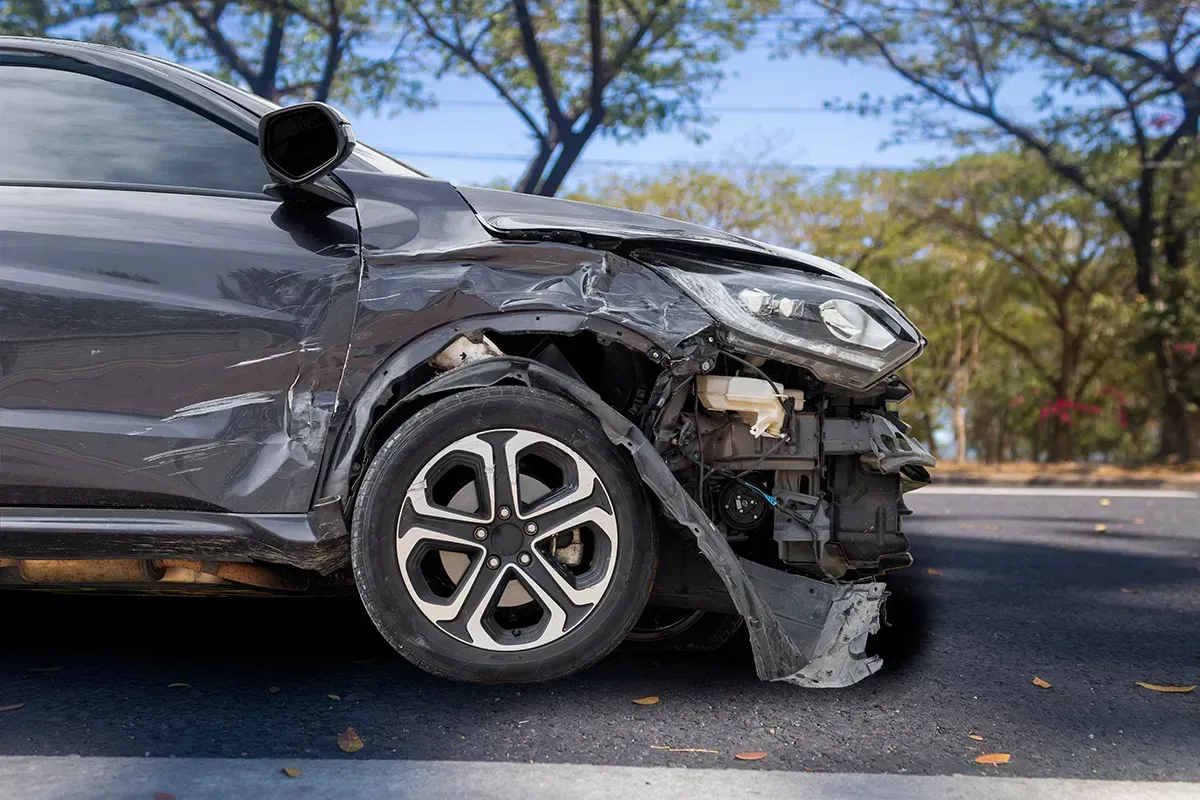Ein Auto mit beschädigter Front steht am Straßenrand.