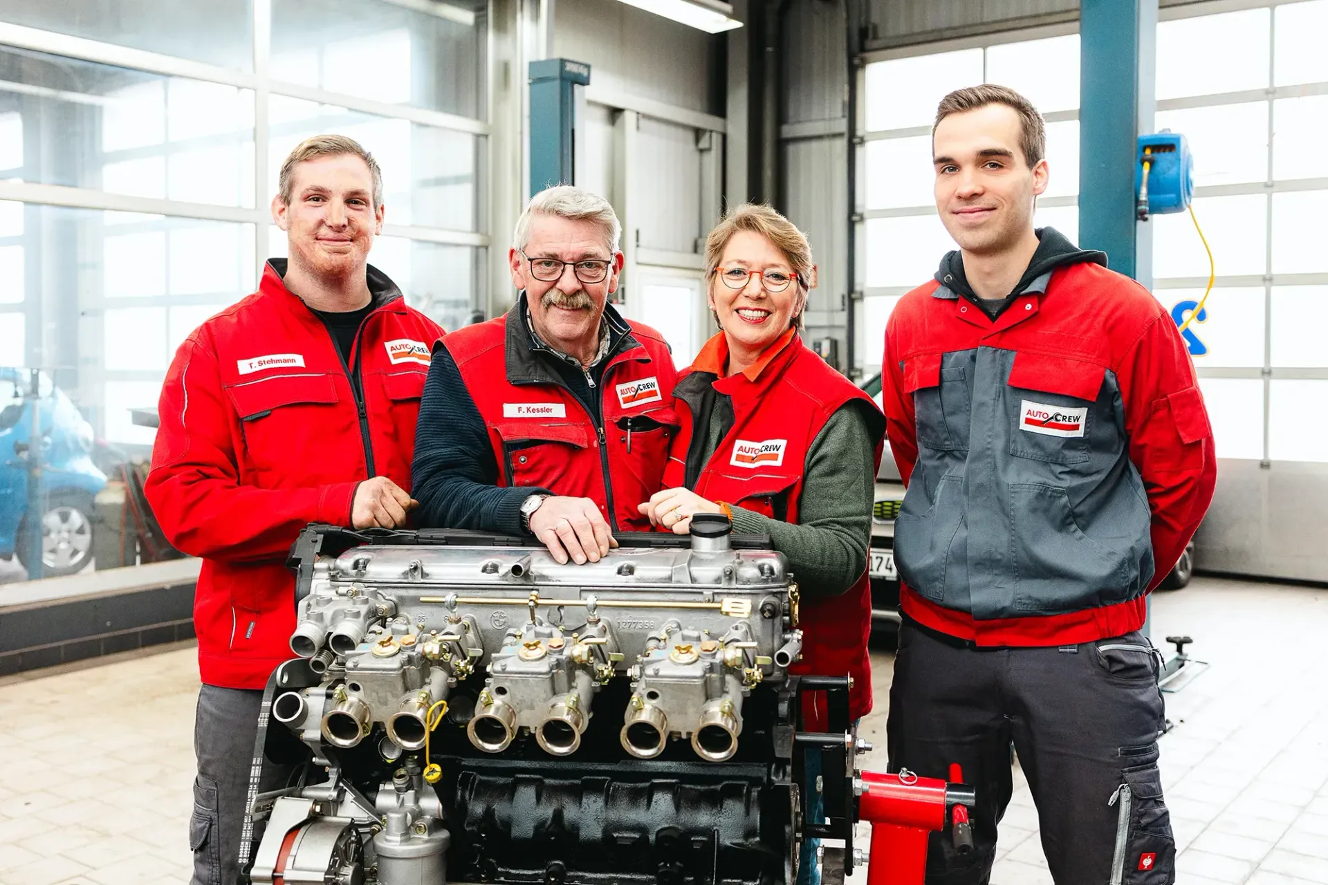 Eine Gruppe von Mechanikern posiert vor einem Automotor für ein Foto.