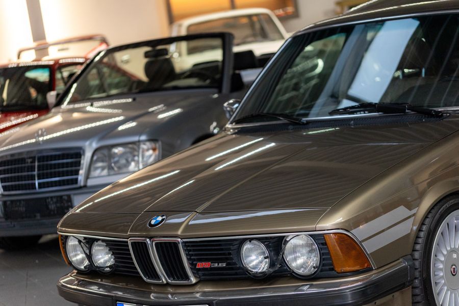 In einem Ausstellungsraum ist eine Reihe von Autos nebeneinander geparkt.