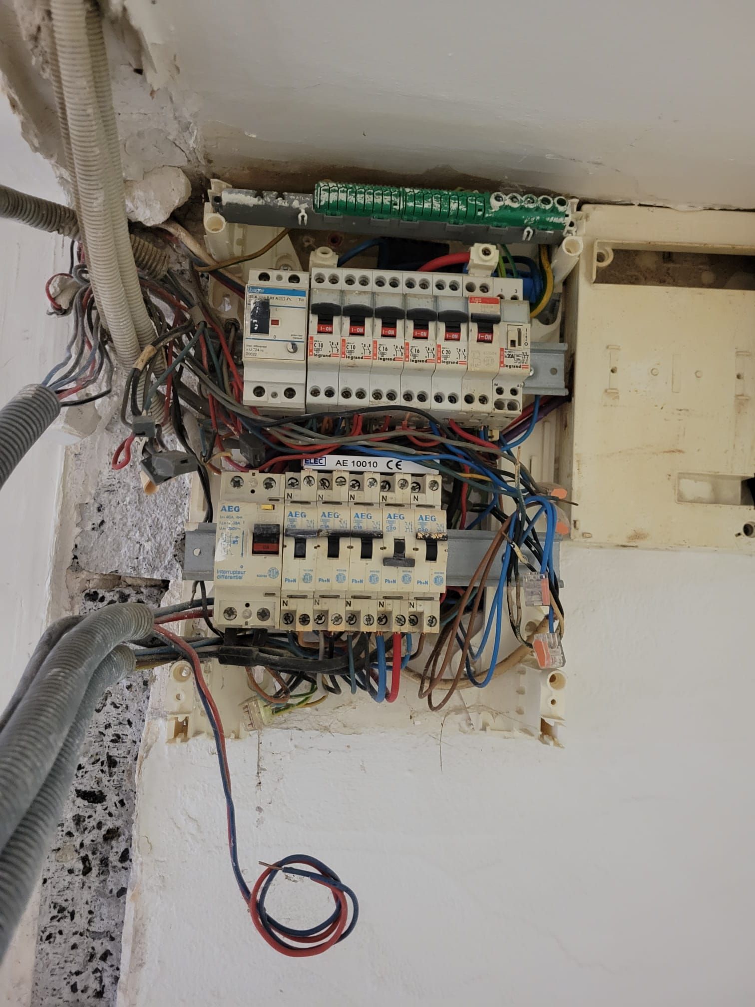 Tableau électrique ouvert avec fils apparents sur un mur