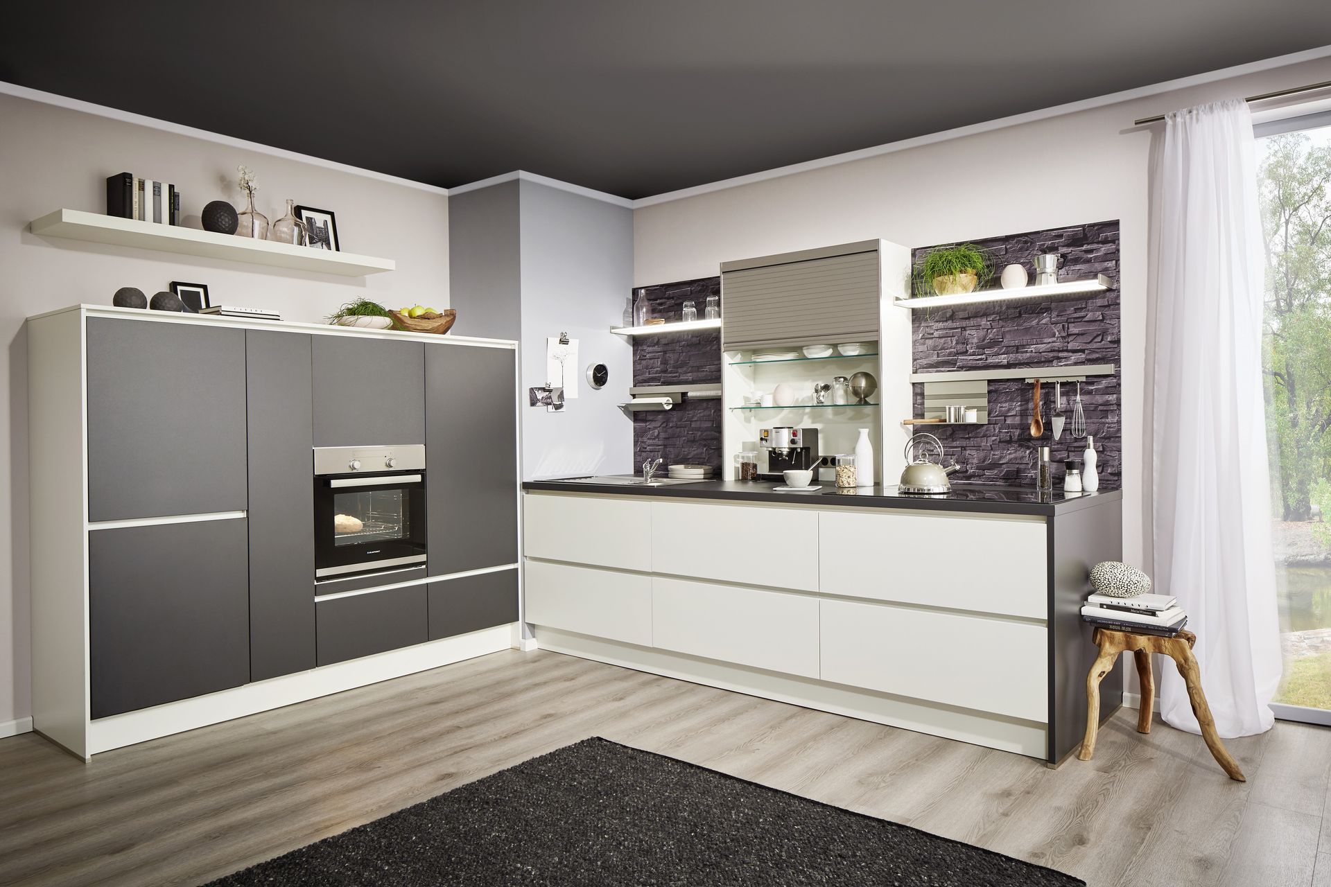 Eine Küche mit grauen und weißen Fronten in einem Raum mit schwarzer Decke. Die Küchenrückwand ist mit Schiefer bedruckt.