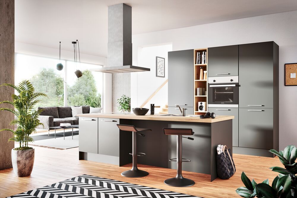 Eine Küche mit einer breiten Insel in der Mitte des Raumes. Ein Teil ist als Theke ausgebaut mit zwei Barhockern