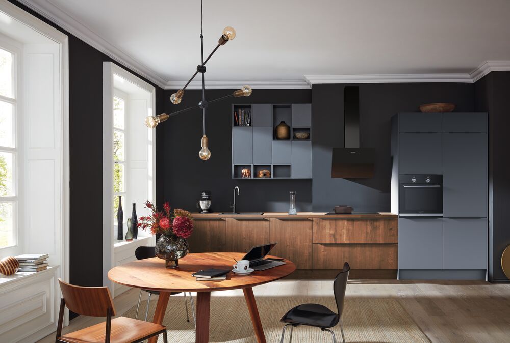 Eine Küche mit Fronten in mattem, dunklem Blau und im Holz-Look.