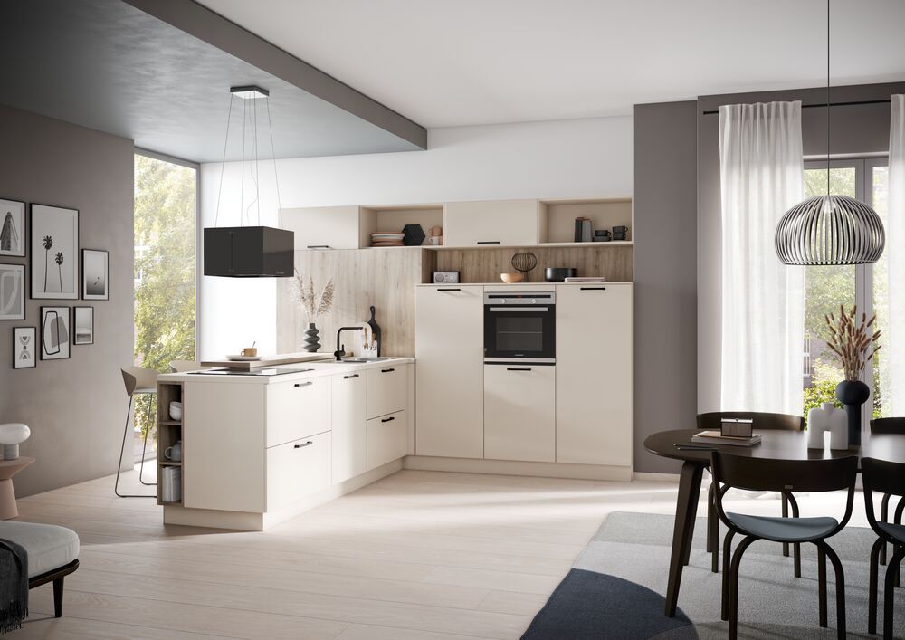 Eine Küche mit creme-weißen Schränken. Über dem Kochfeld befindet sich eine frei hängende Abzugshaube.