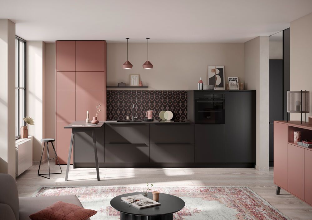 Eine Küche mit rosafarbenen und schwarzen Schränken in einem offenen Wohnzimmer.