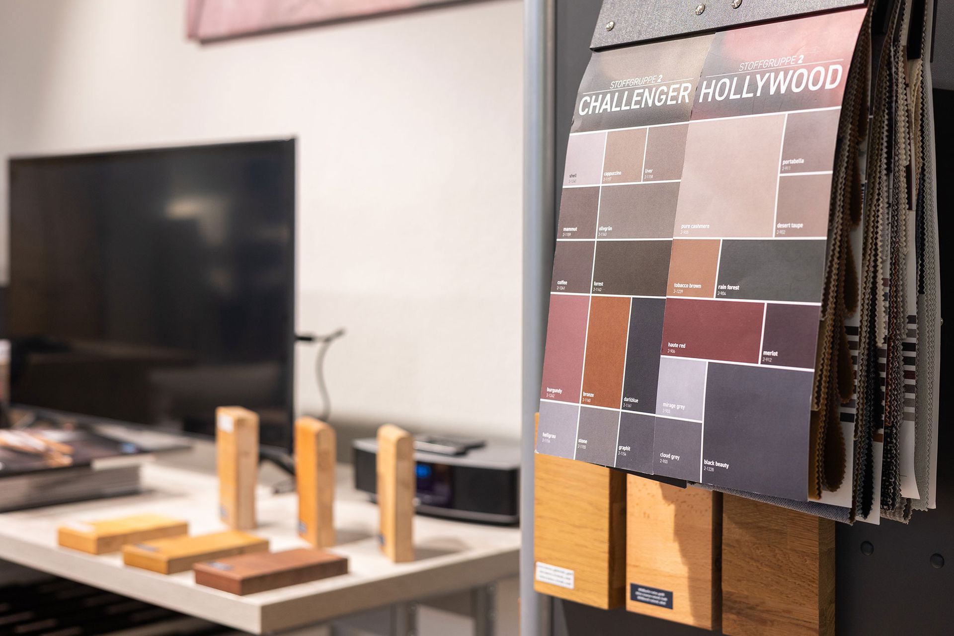 Farbmuster und Holzproben hängen neben einem Schreibtisch mit Fernseher.