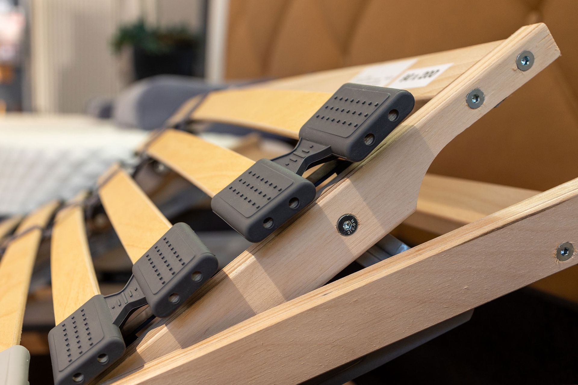 Verstellbarer Bettrahmen mit grauen Kunststoffgelenken und Holzlatten.