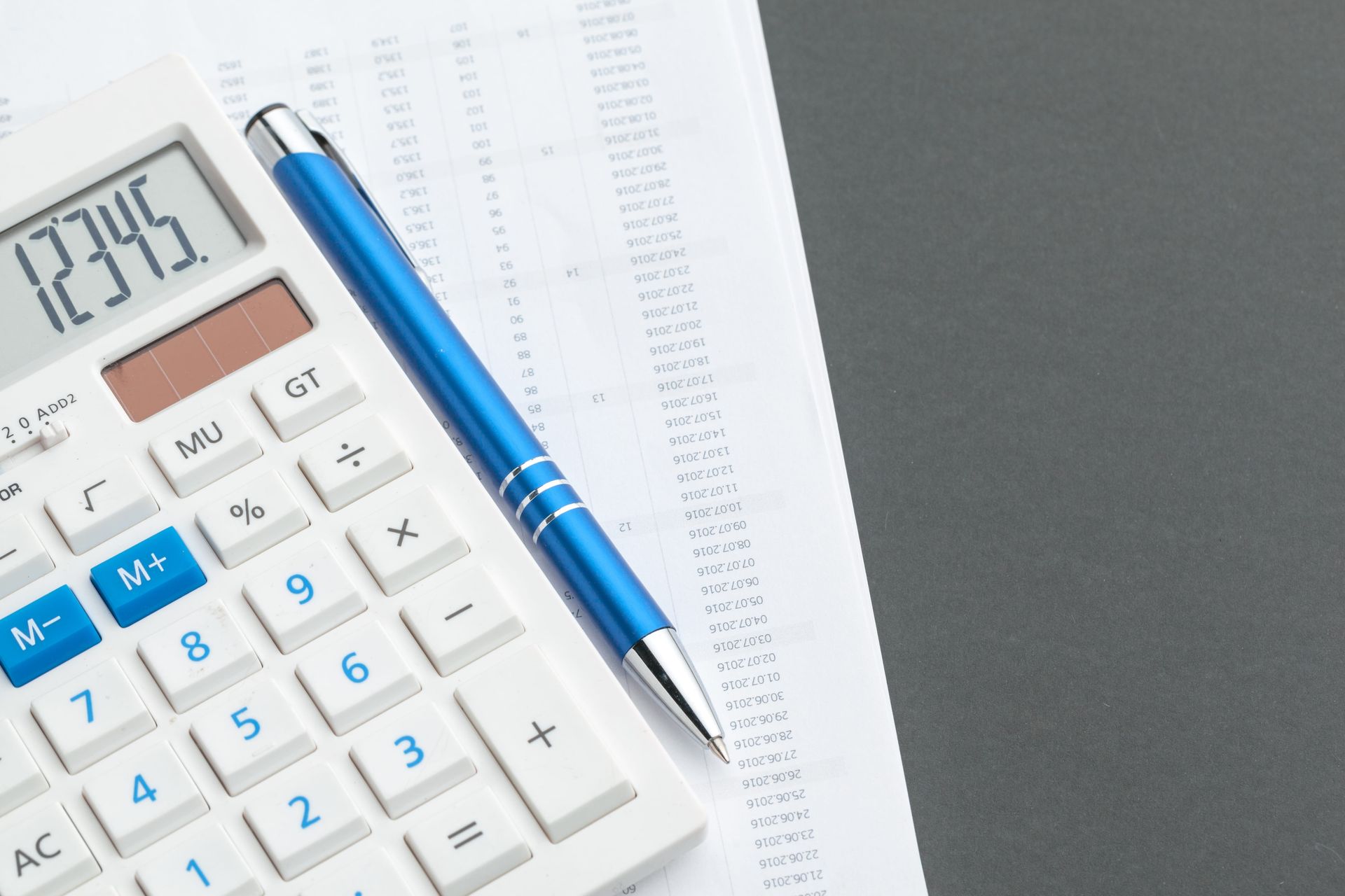 Calculadora con un bolígrafo azul sobre documentos financieros y un recibo a la vista
