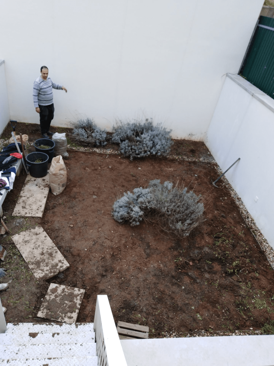 Um homem está parado no meio de um quintal de terra
