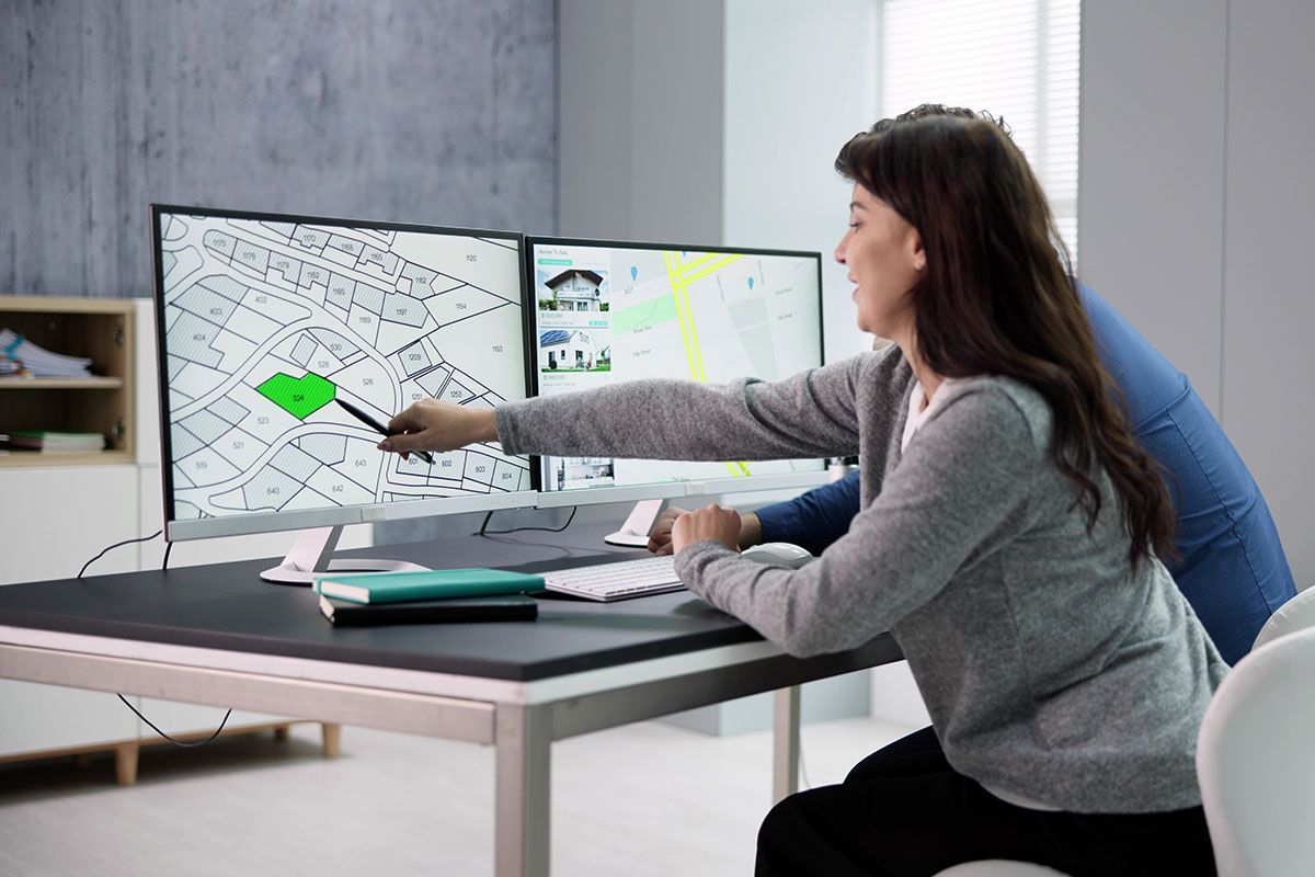 Deux géomètres qui regardent des parcelles de terrain sur un plan sur ordinateur