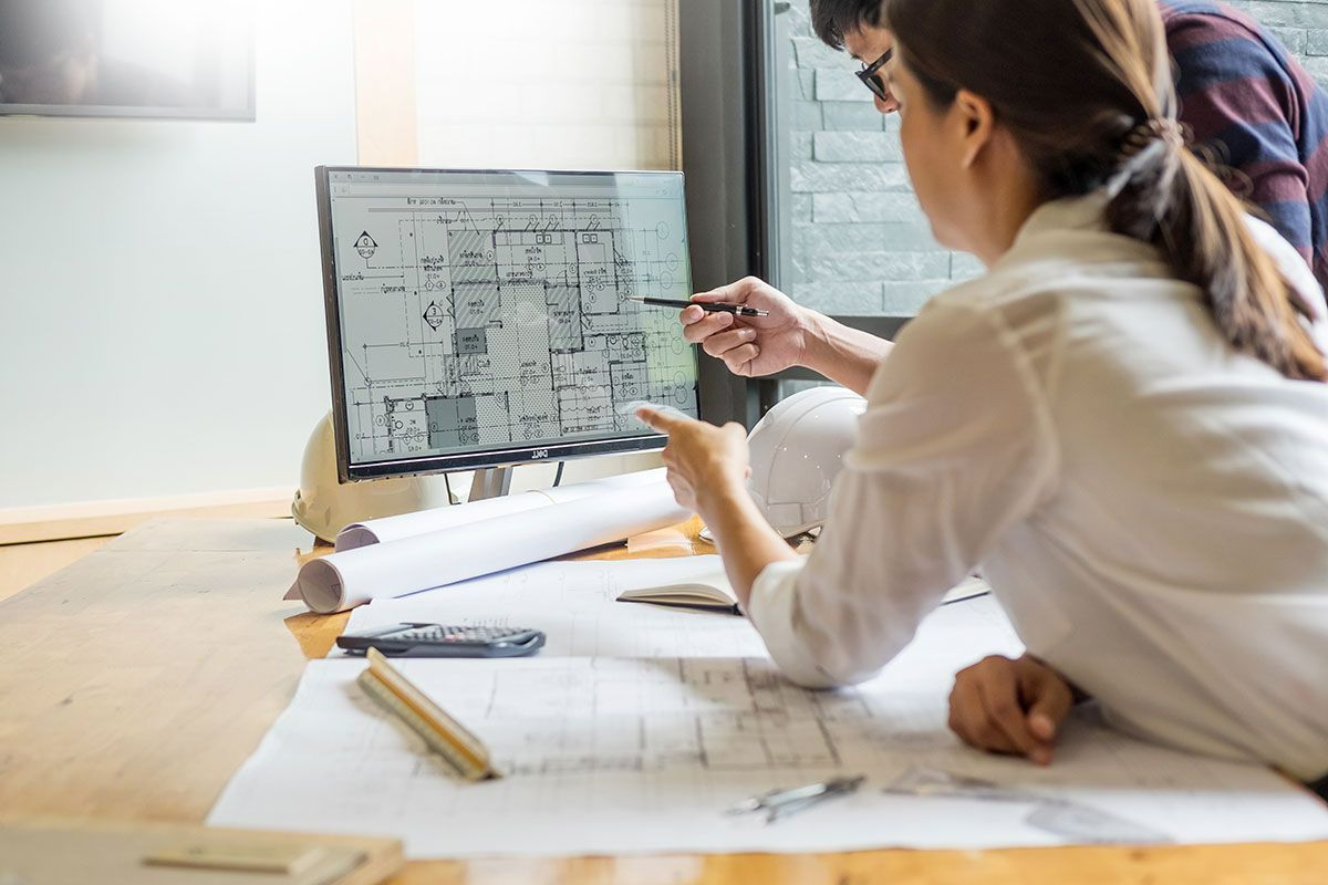 Discussion entre deux personnes au sujet d'un plan de bâtiment sur ordinateur