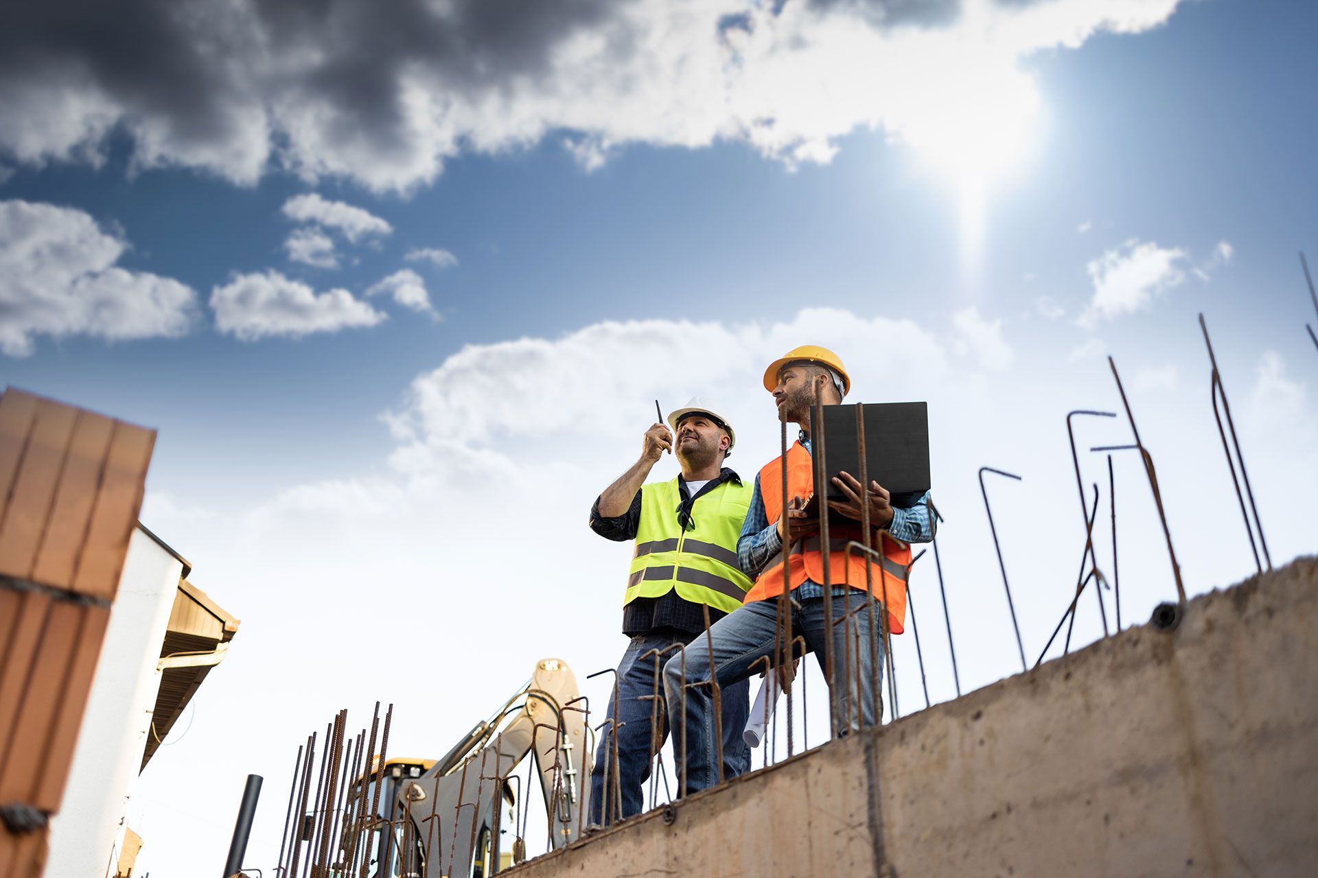 Deux hommes sur un chantier avec un ordinateur et un talkie-walkie