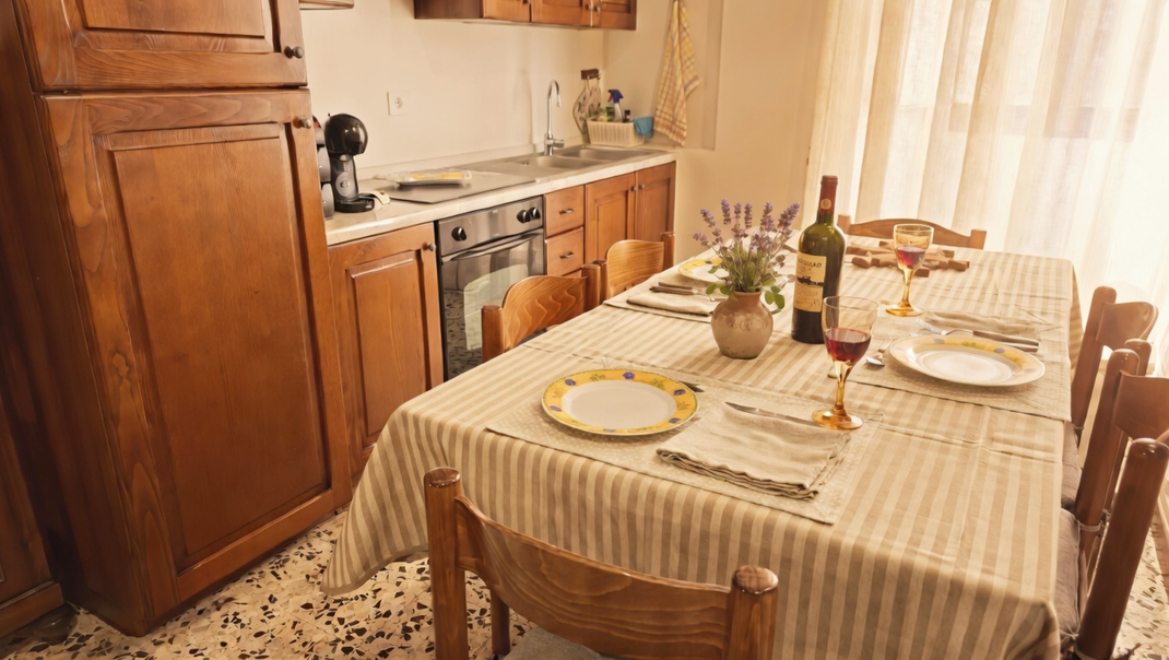 Sala da pranzo con tavolo apparecchiato e cucina in legno dell'appartamento