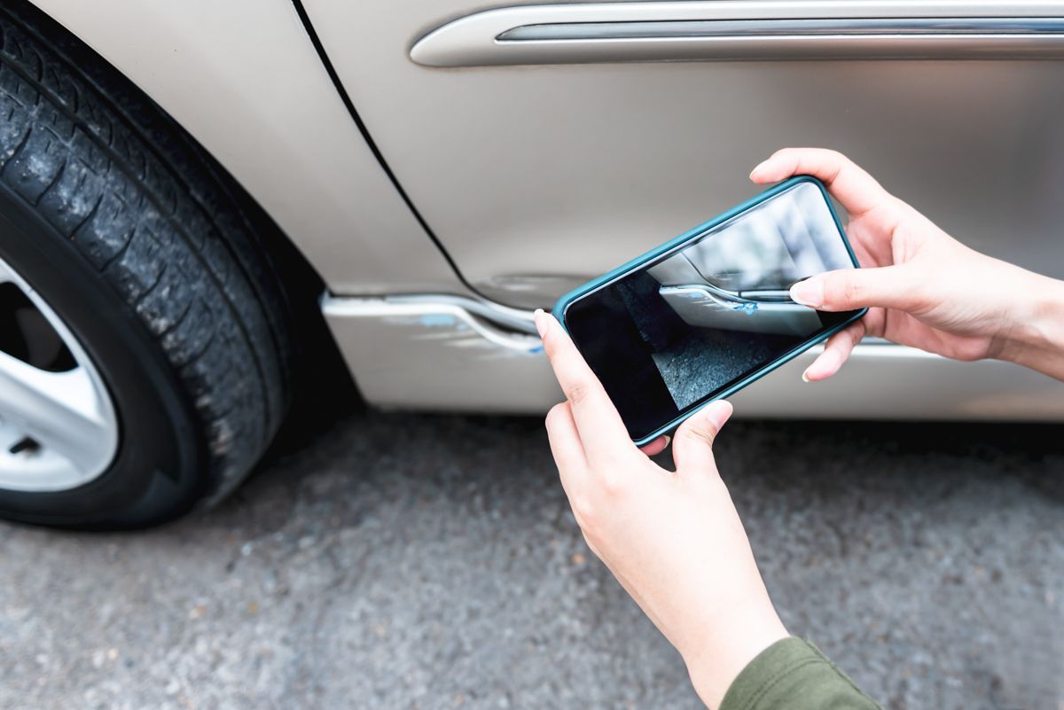 eine Person fotografiert ein Auto mit einem Handy
