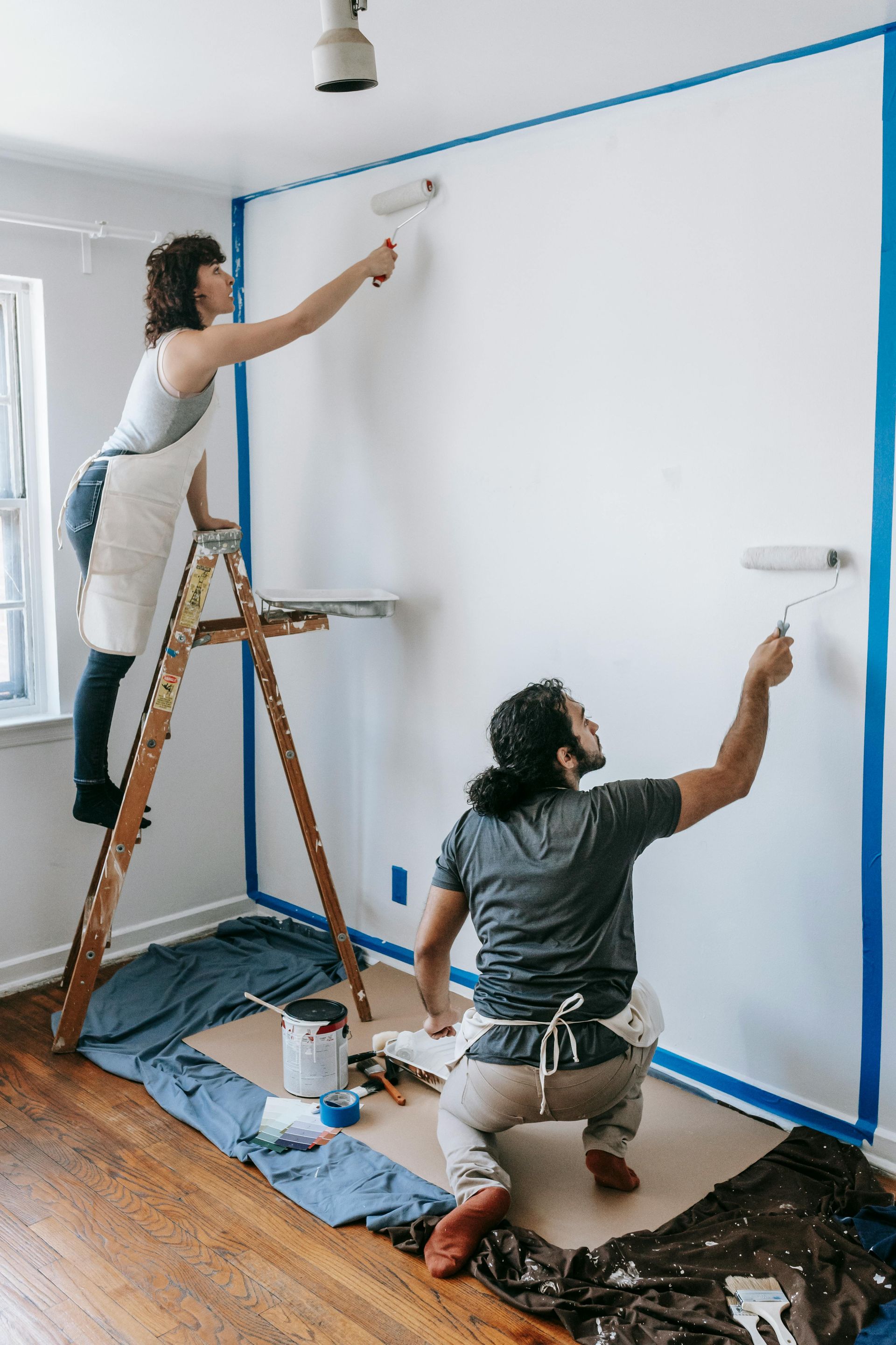 Un hombre y una mujer están pintando una pared en una habitación.