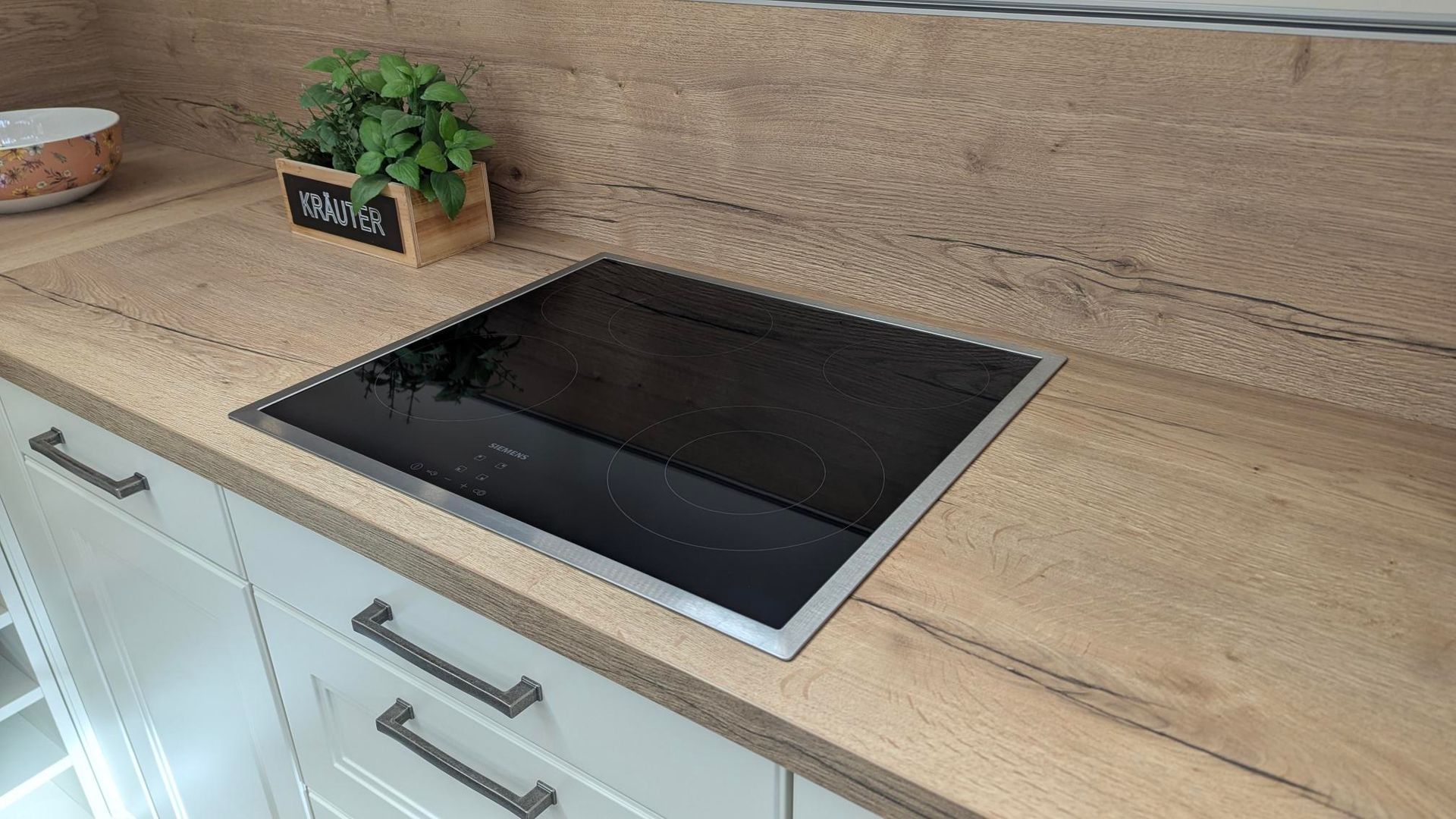 In einer Küche steht auf einer Holztheke ein Herd mit Backofen.