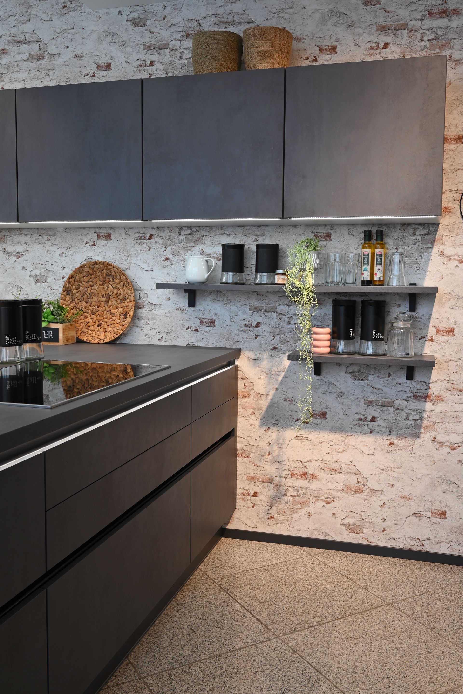 Eine Küche mit Backsteinwand und schwarzen Schränken